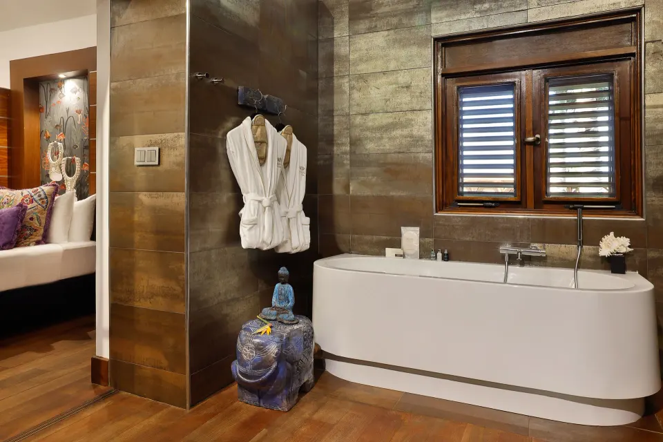 Indoor bathroom with freestanding bathtub and robes hanging on the wall at Baoase Luxury Resort