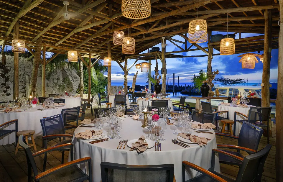 Thatched open-air dining set for a banquet with ocean view at Baoase Luxury Resort