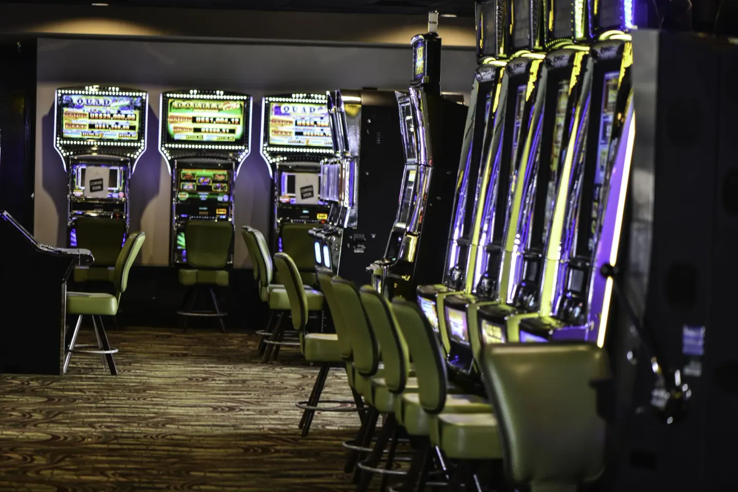 Rows of illuminated slot machines and stools in the casino at Barceló Aruba.