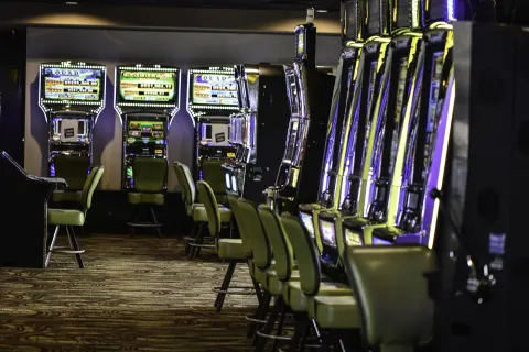 Rows of illuminated slot machines and stools in the casino at Barceló Aruba.