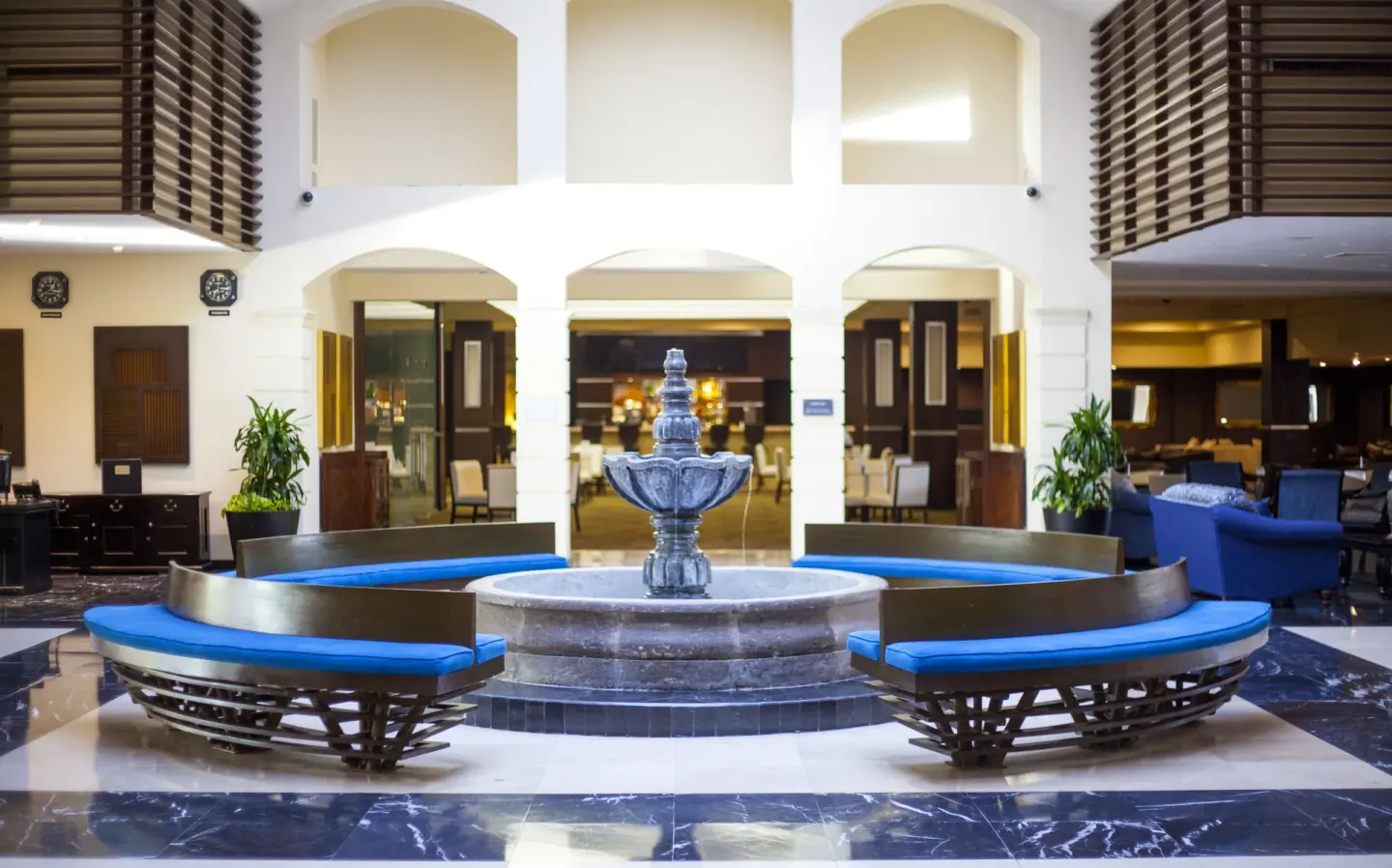 Lobby fountain with curved blue benches and arched walls at Barceló Aruba.