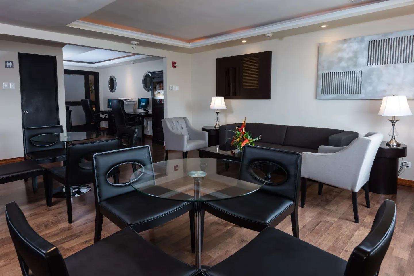 Lounge with glass tables, sofa seating, and work desks at Barceló Aruba.