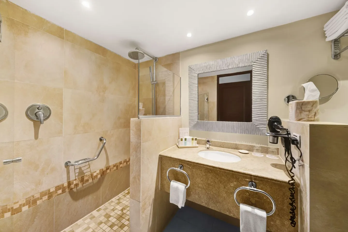 Bathroom with walk-in shower, vanity mirror, and towels at Barceló Aruba.