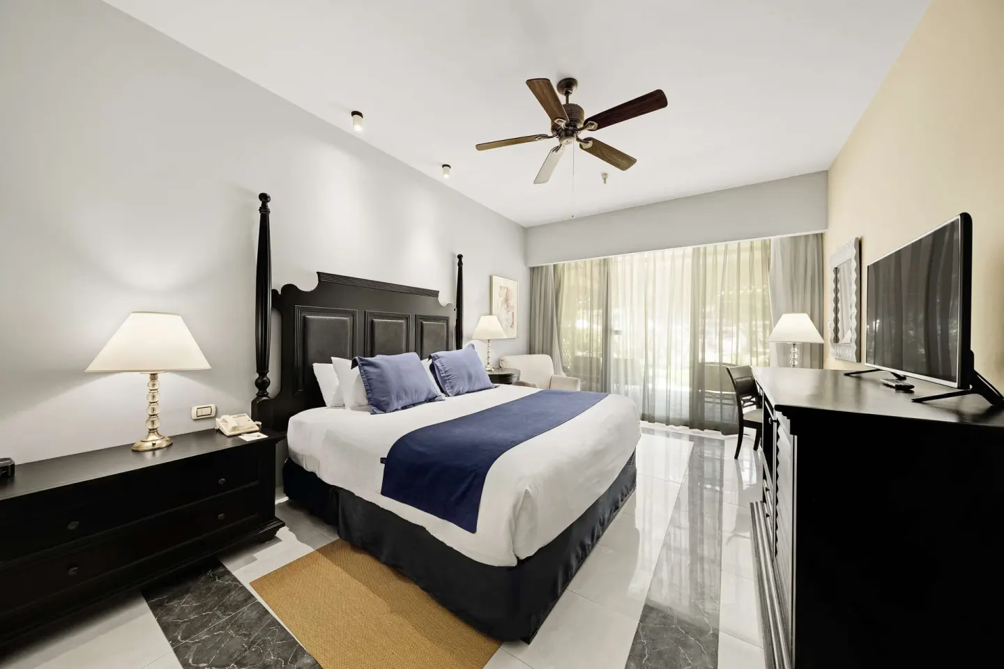King bed guest room with balcony curtains and TV dresser at Barceló Aruba.