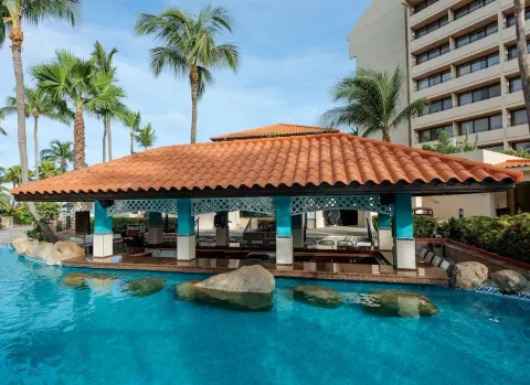Closer view of the poolside pavilion with palms and hotel rooms at Barceló Aruba.