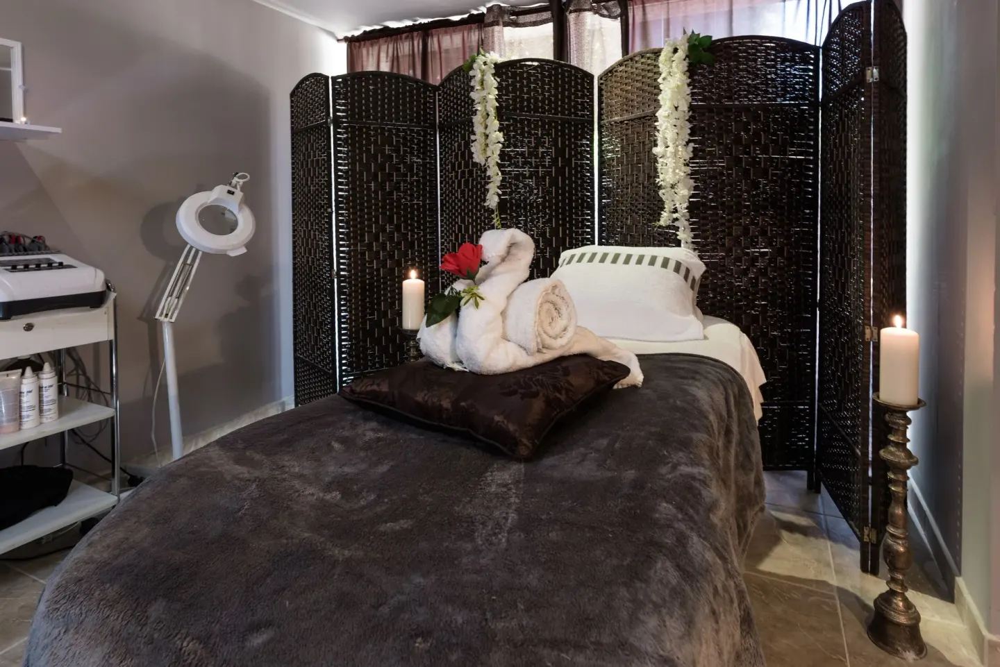 Spa treatment bed with towels, candles, and woven screen at Barceló Aruba.