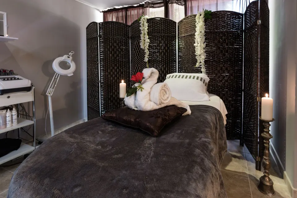 Spa treatment bed with towels, candles, and woven screen at Barceló Aruba.