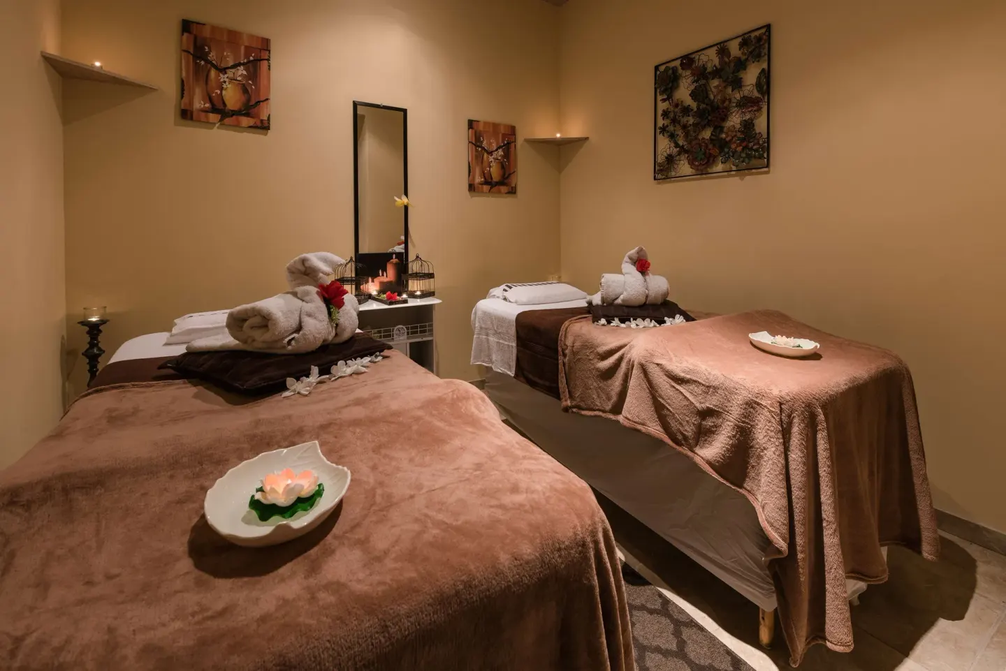 Spa treatment room with two massage beds, towels, candles, and wall art at Barceló Aruba.