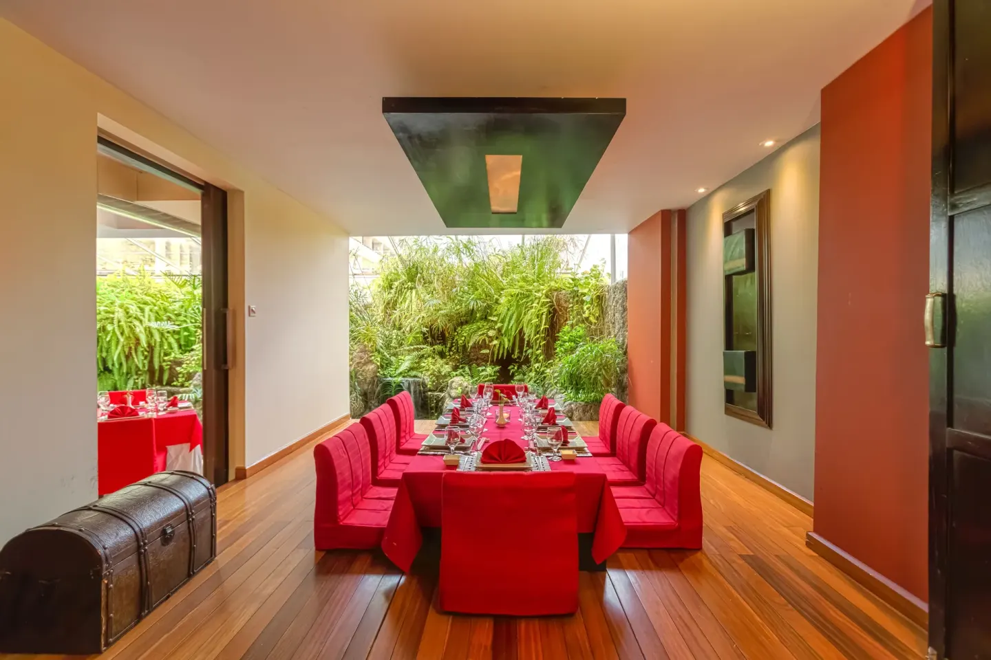 A long red-draped dining table is set in a private room at Barceló Aruba.