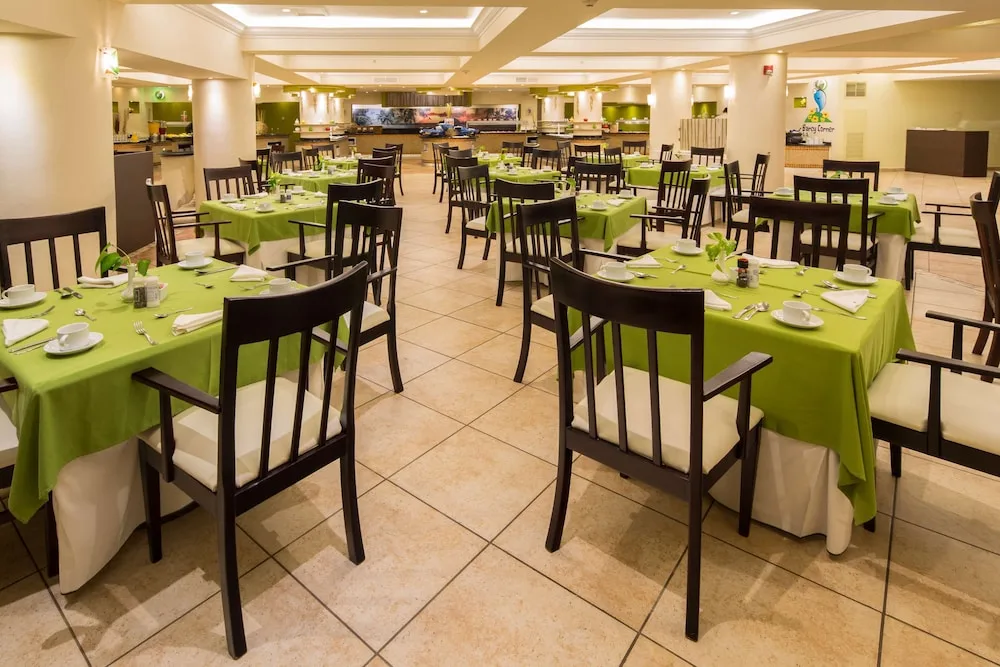 Large buffet dining room with green tablecloths and set tables at Barceló Aruba.