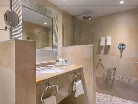 Deluxe Room bathroom with vanity, mirror, and glass shower at Barceló Aruba.