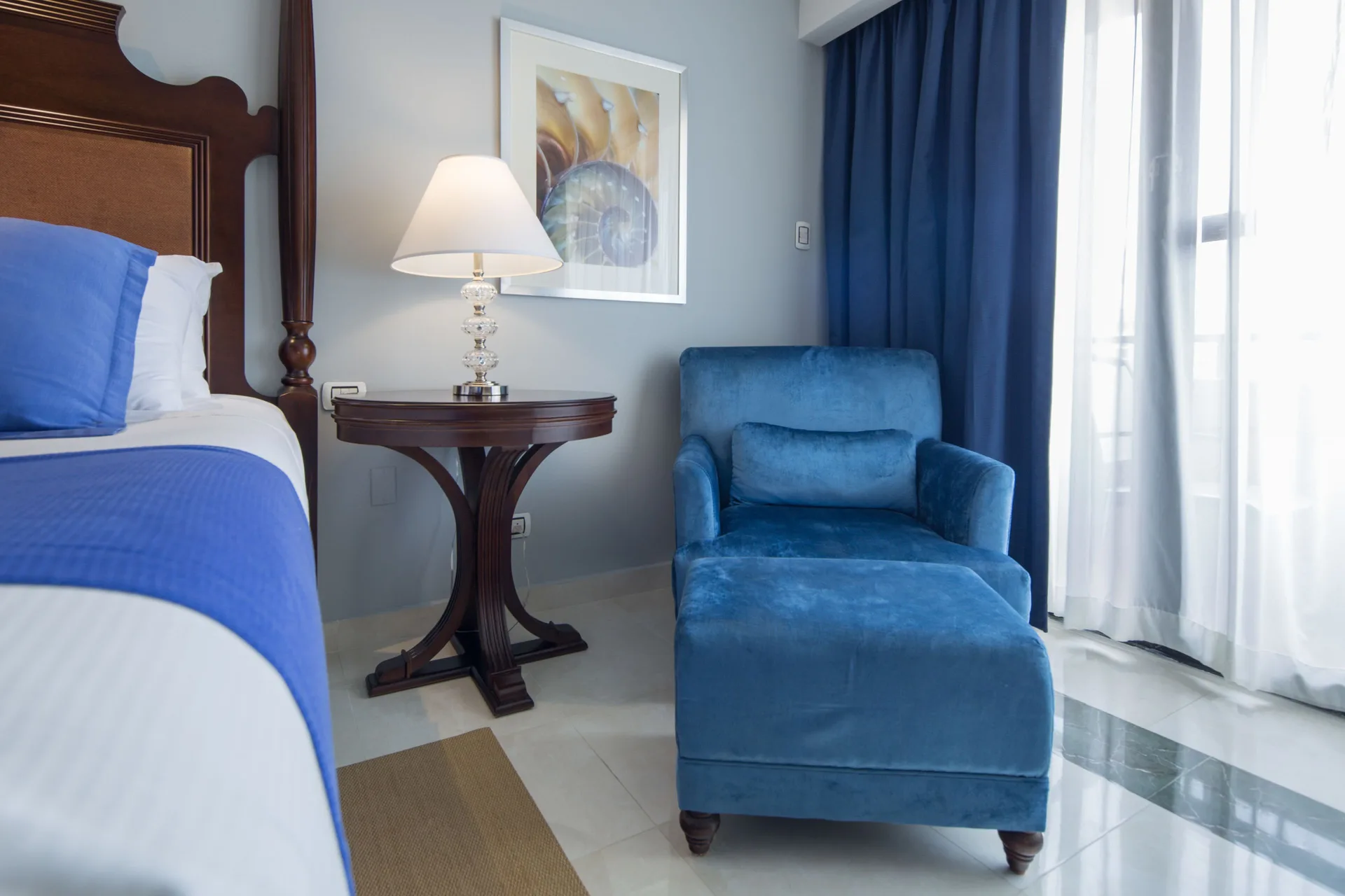 Deluxe Room bed and blue lounge chair beside the window at Barceló Aruba.