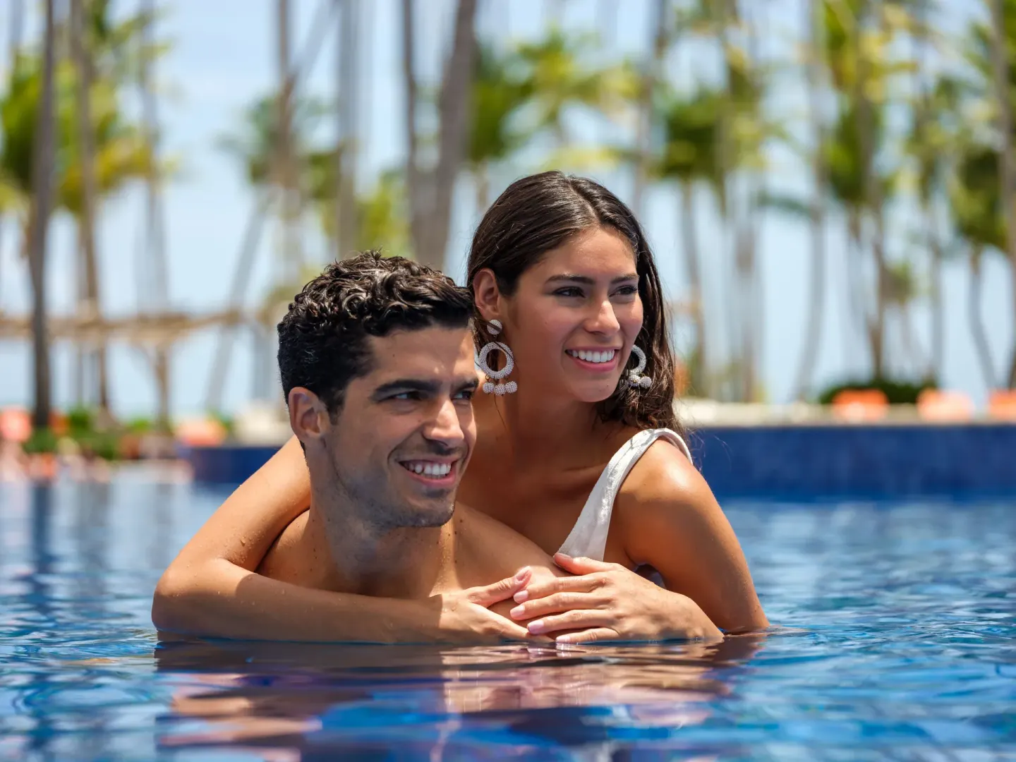 Couple smiling in the pool with palms behind them at Barceló Bávaro Beach.