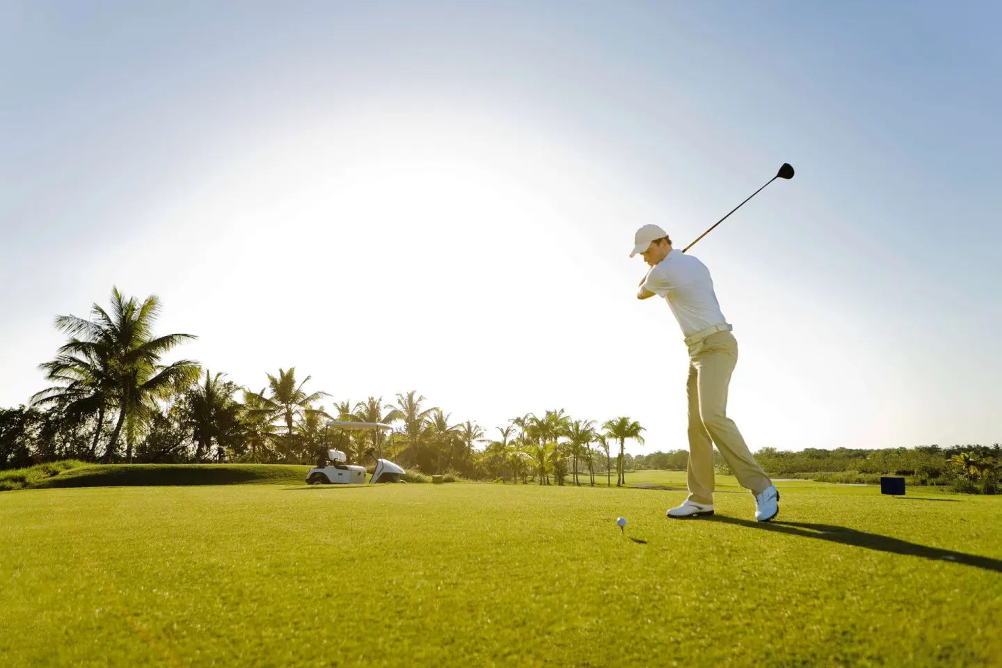 A golfer swings from a sunlit tee box at Barceló Bávaro Beach.