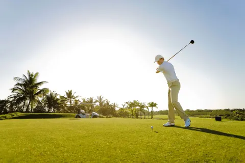 A golfer swings from a sunlit tee box at Barceló Bávaro Beach.