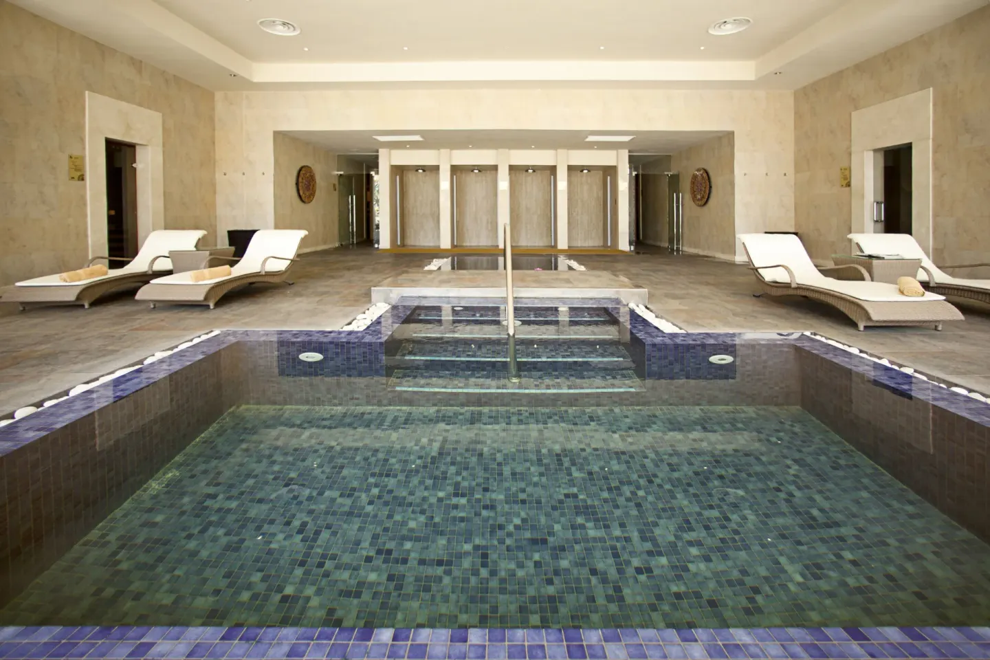 Indoor spa pool with loungers and tiled steps at Barceló Bávaro Beach.