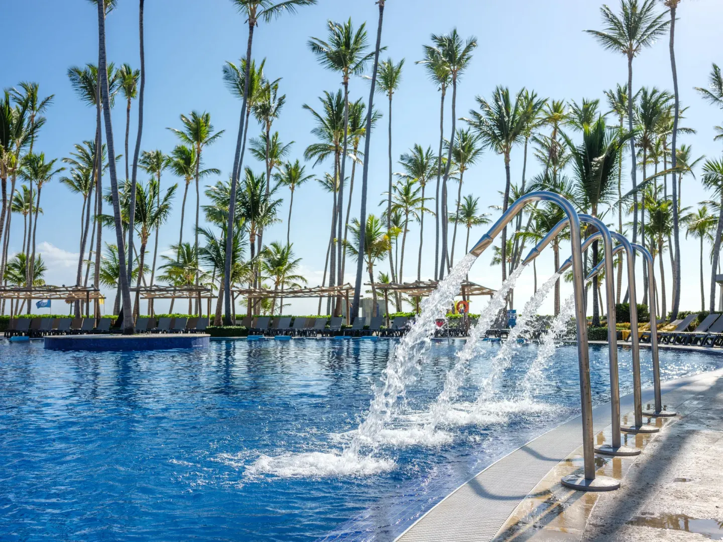 Pool water features spraying into a palm-lined pool at Barceló Bávaro Beach.