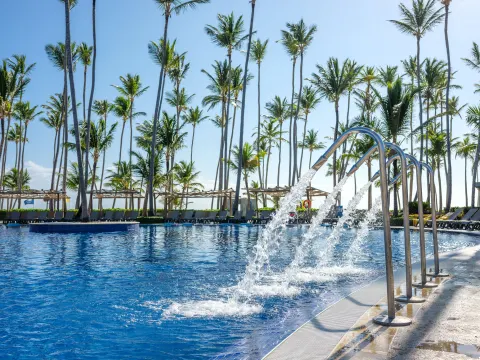 Pool water features spraying into a palm-lined pool at Barceló Bávaro Beach.