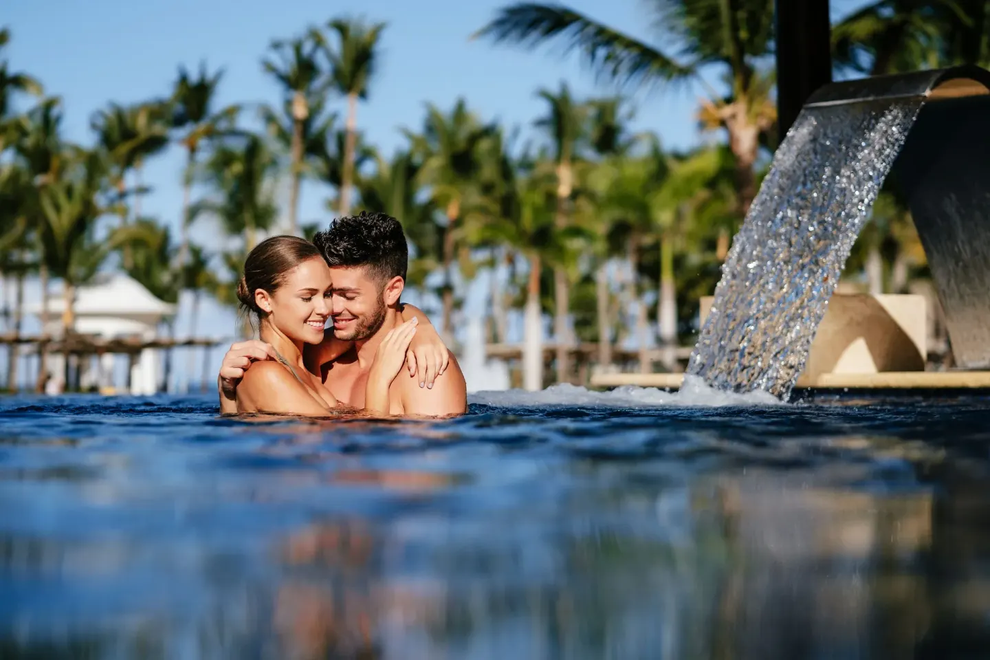 Couple embracing in the pool beside a waterfall feature at Barceló Bávaro Beach.