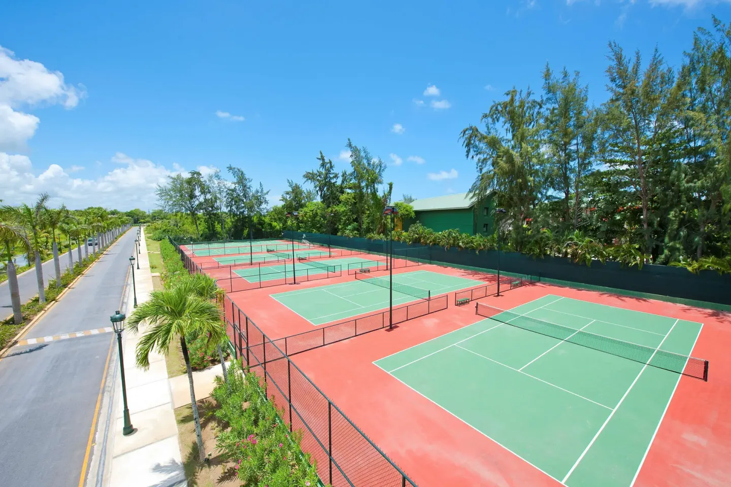 Outdoor tennis courts beside a palm-lined road at Barceló Bávaro Beach.