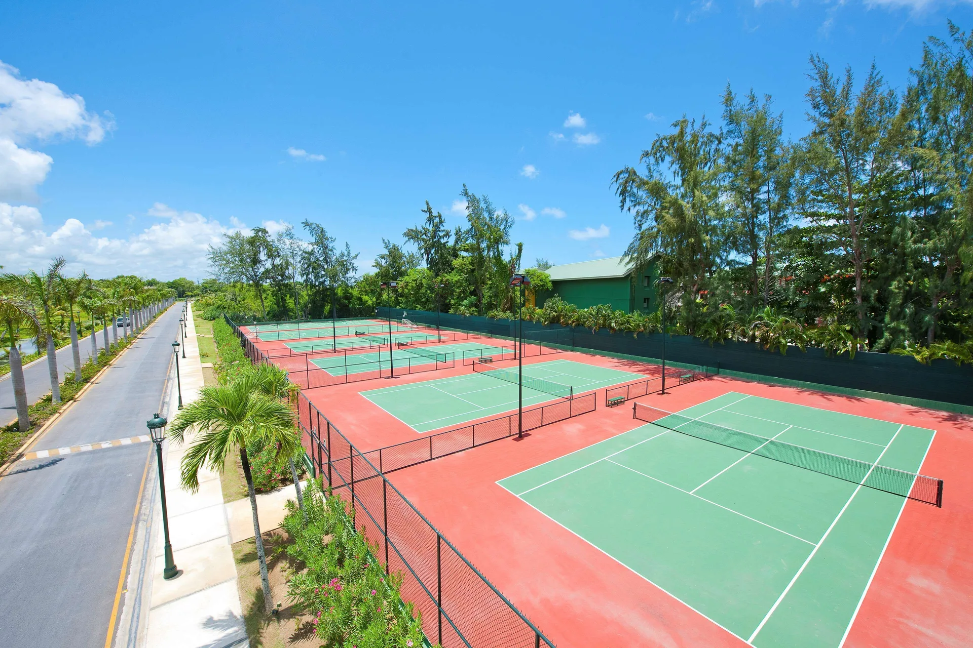 Outdoor tennis courts beside a palm-lined road at Barceló Bávaro Beach.