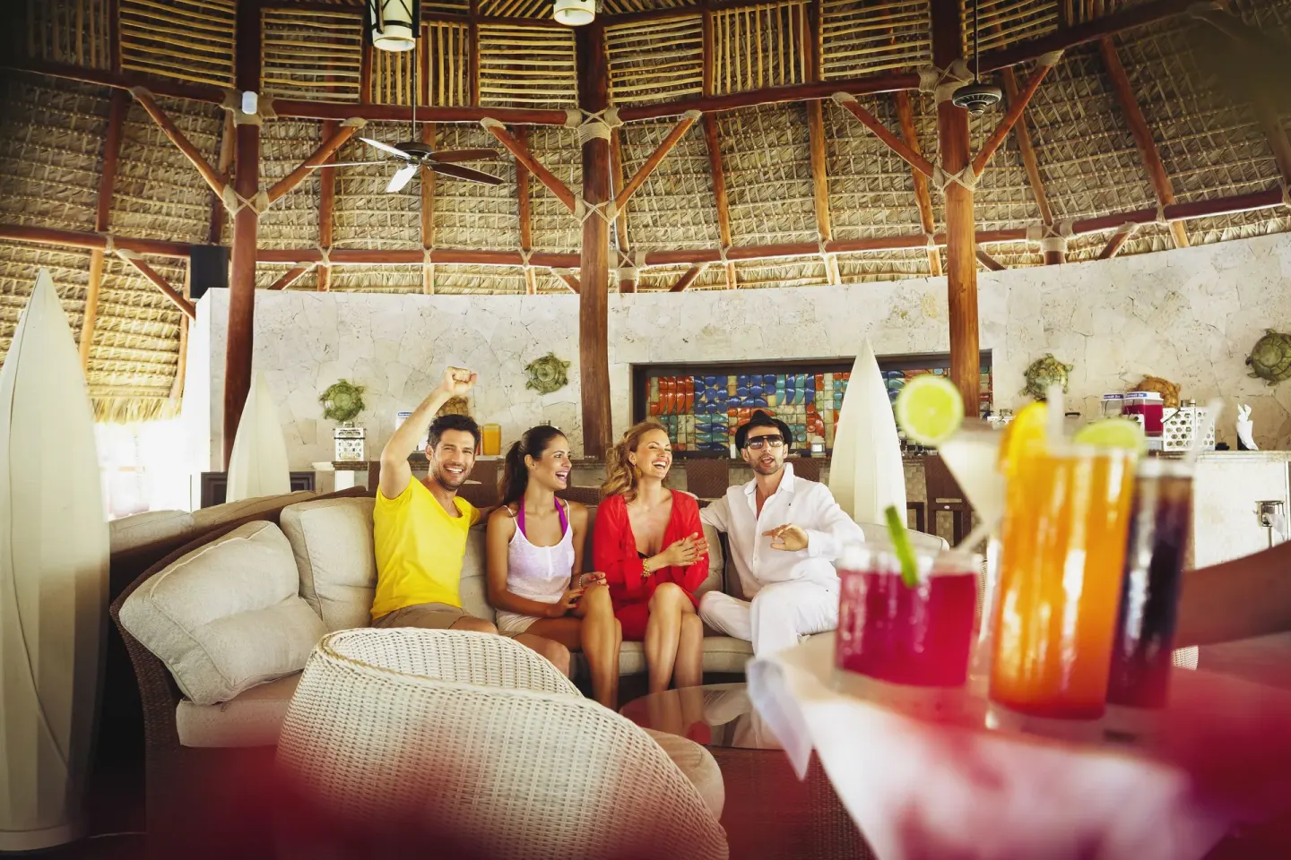Guests enjoy colorful drinks in a thatched lounge at Barceló Bávaro Beach.