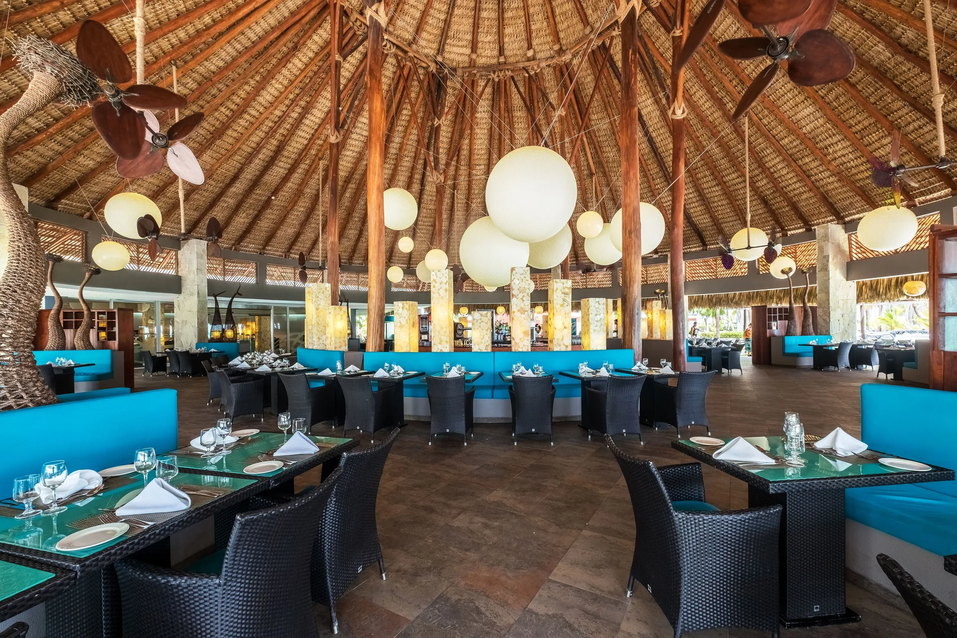 Thatched-roof restaurant dining room with turquoise seating at Barceló Bávaro Beach.