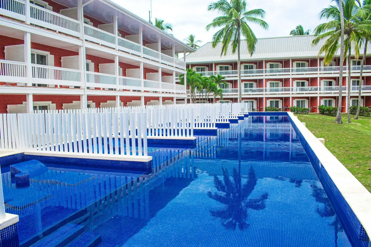 Superior Room Swim Up pool lane beside red guest buildings at Barceló Bávaro Beach.