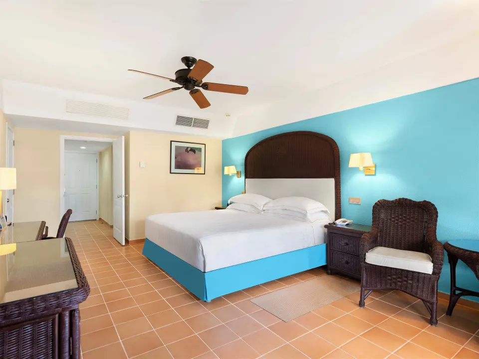 Superior Room king bed with wicker chair and desk at Barceló Bávaro Beach.