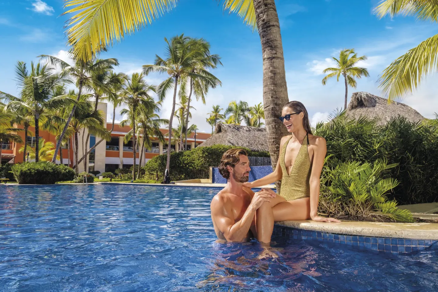 Couple relaxing at the edge of a palm-lined pool at Barceló Bávaro Palace.
