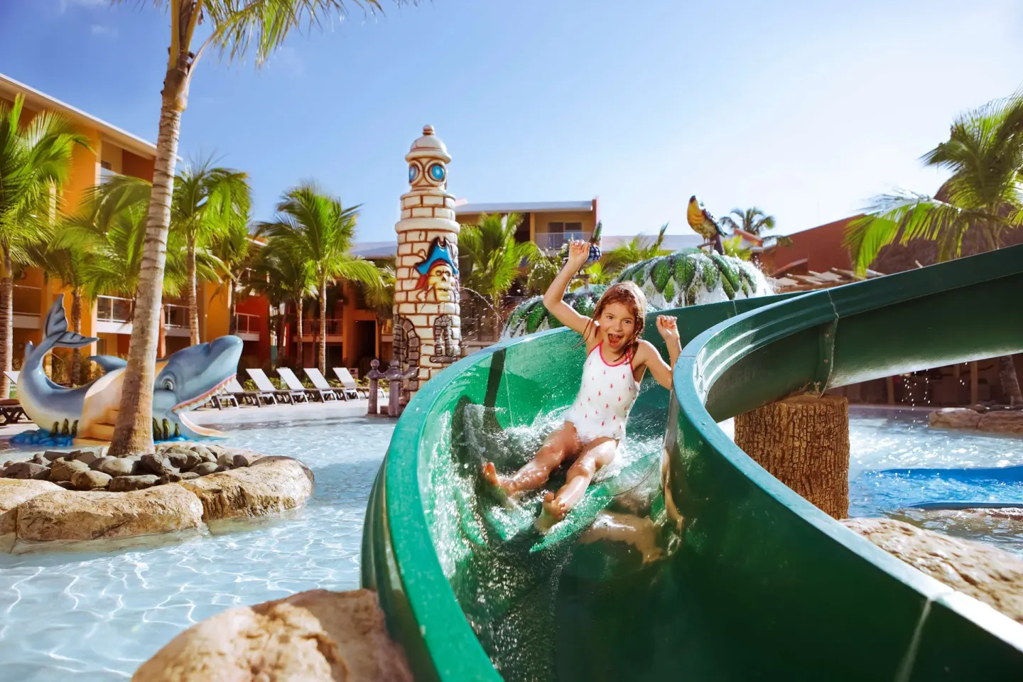 Child rides a green waterslide in the kids' pool at Barceló Bávaro Palace.