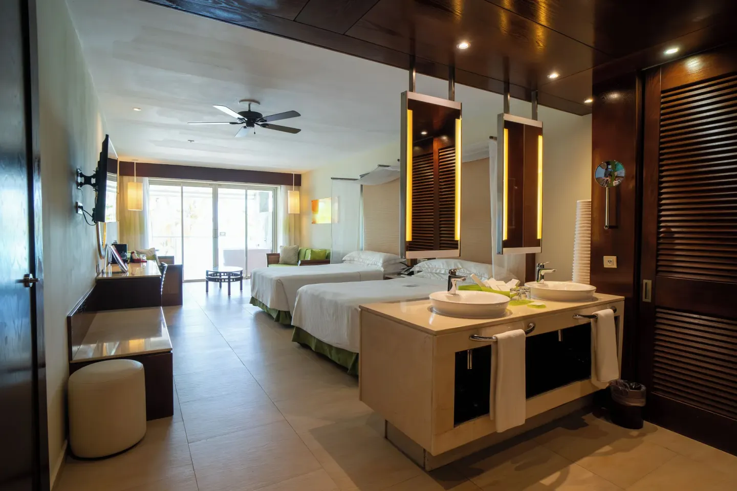 Guest room with two beds, open vanity sinks, desk, and balcony doors at Barceló Bávaro Palace.