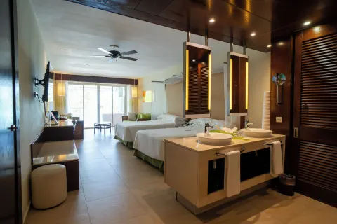Guest room with two beds, open vanity sinks, desk, and balcony doors at Barceló Bávaro Palace.