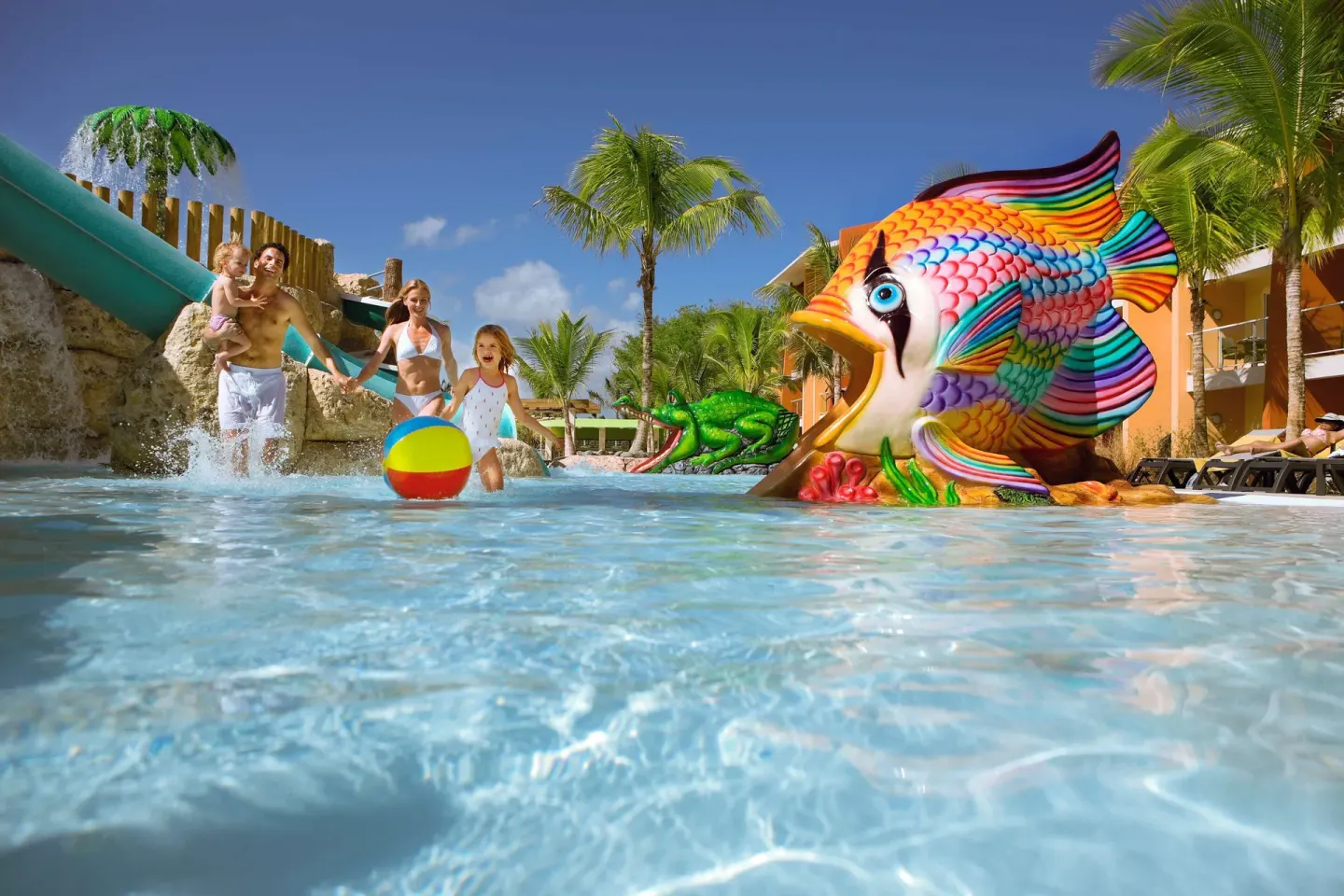 Family plays in the kids' pool with a fish slide at Barceló Bávaro Palace.