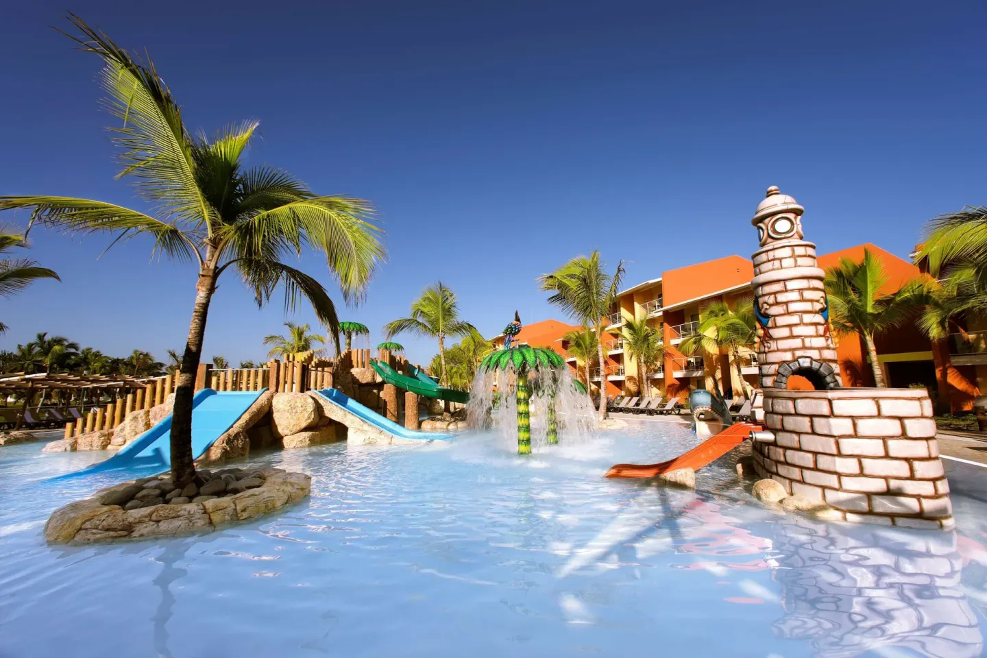 Colorful kids' pool with slides, palm trees, and a lighthouse feature at Barceló Bávaro Palace.