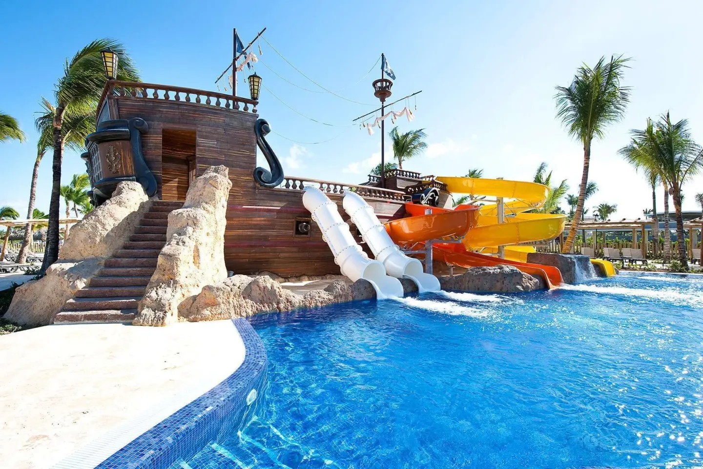 Pirate ship water slides extend into a bright pool at Barceló Bávaro Palace.
