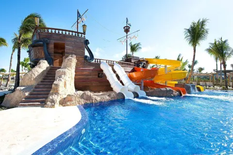 Pirate ship water slides extend into a bright pool at Barceló Bávaro Palace.
