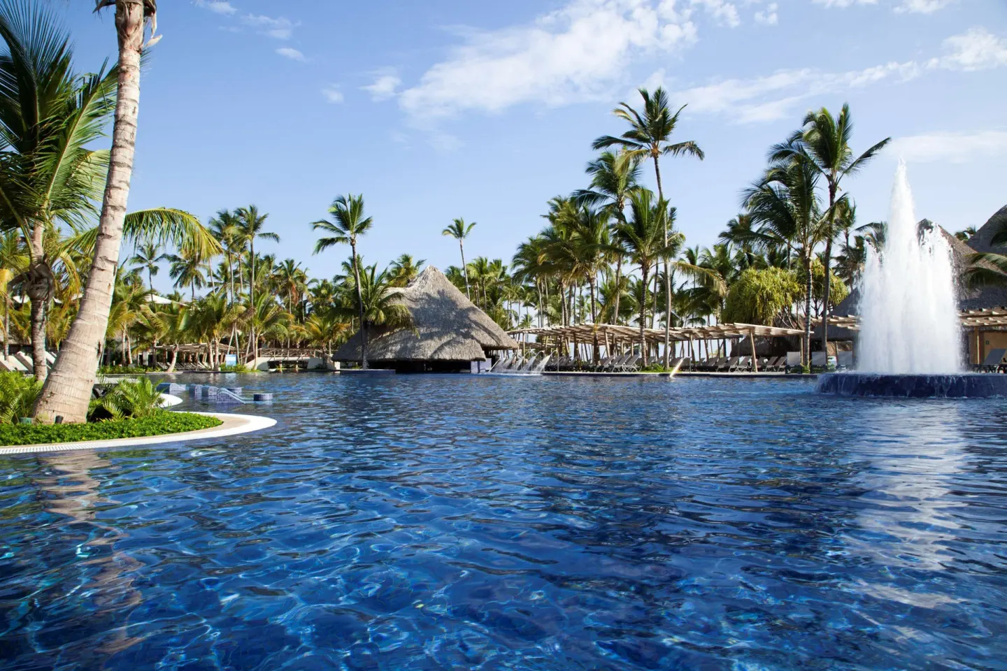 A large resort pool with a fountain and palm trees at Barceló Bávaro Palace.