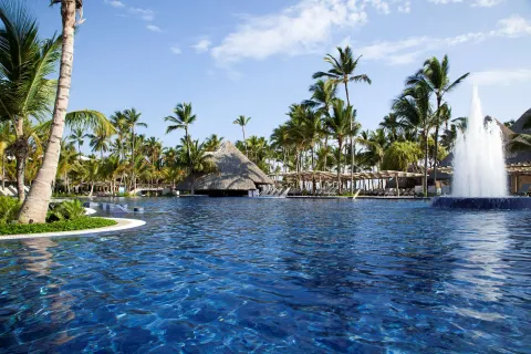 A large resort pool with a fountain and palm trees at Barceló Bávaro Palace.