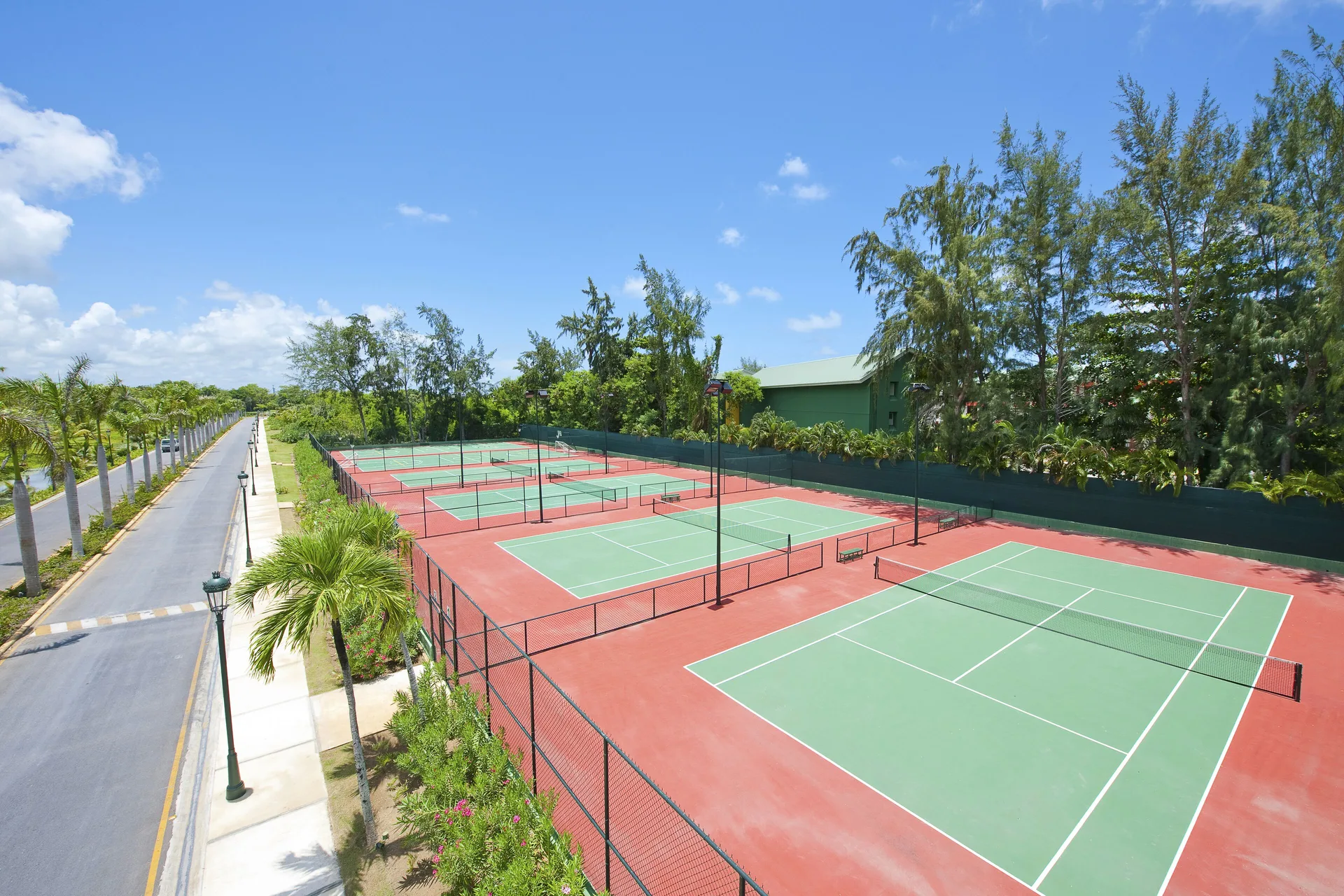 Outdoor tennis courts beside a palm-lined road at Barceló Bávaro Palace.