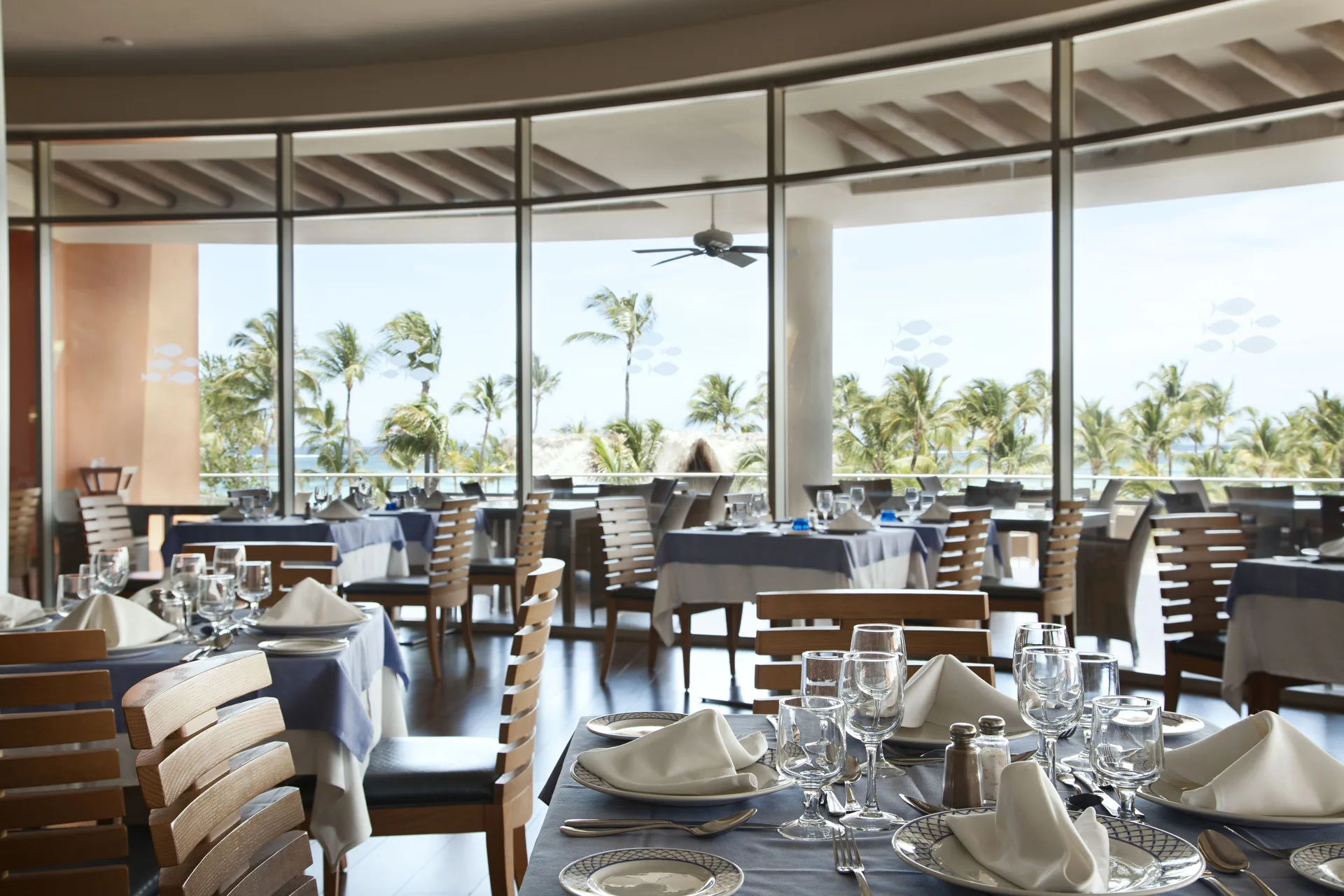 A seafood restaurant dining room overlooks palms and the ocean at Barceló Bávaro Palace.