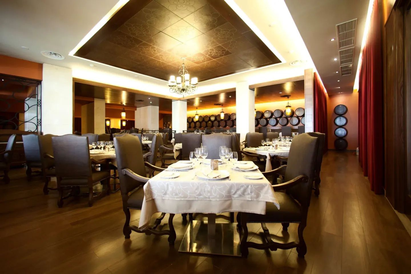 Formal dining room with round tables, wine barrels, and chandelier at Barceló Bávaro Palace.