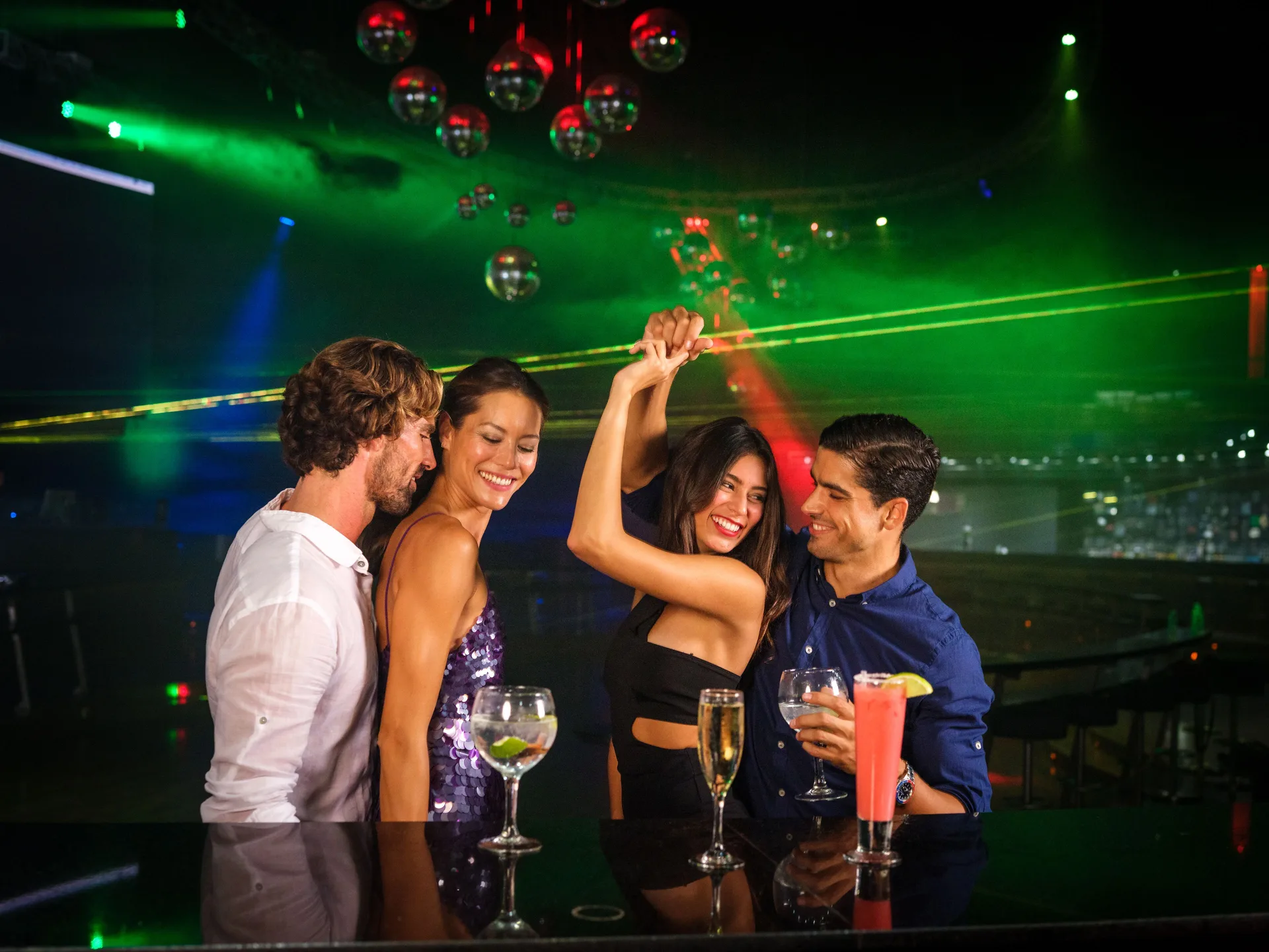 Guests dancing with cocktails under laser lights at Barceló Bávaro Palace.