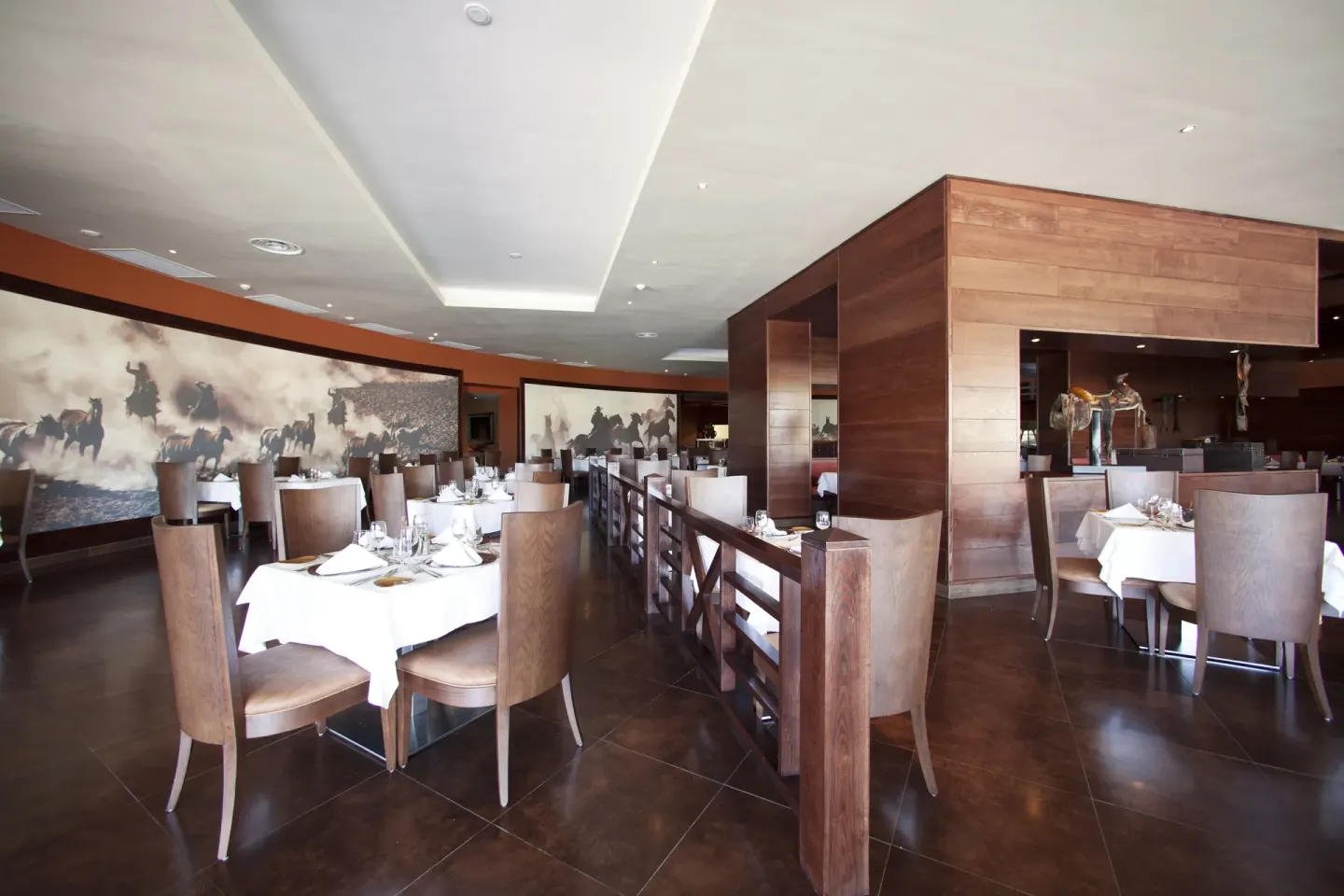 A steakhouse dining room with horse murals and wood partitions at Barceló Bávaro Palace.
