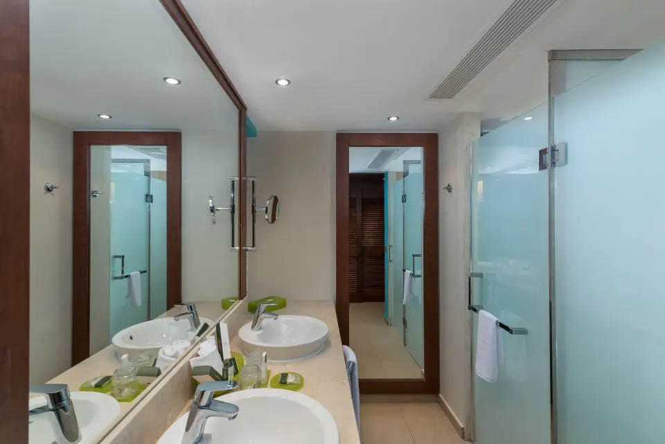 Family Duplex bathroom with double sinks, mirrors and frosted glass shower at Barceló Bávaro Palace.