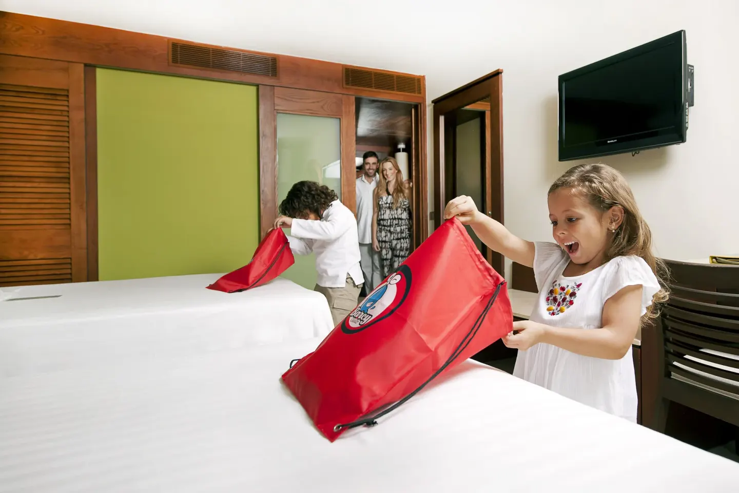 Family Room beds with children unpacking red bags at Barceló Bávaro Palace.