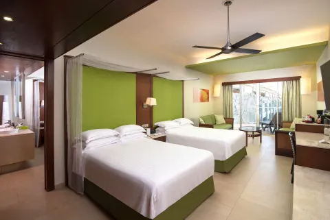 Junior Suite family Premium Level with two beds, balcony doors, and sitting area at Barceló Bávaro Palace.