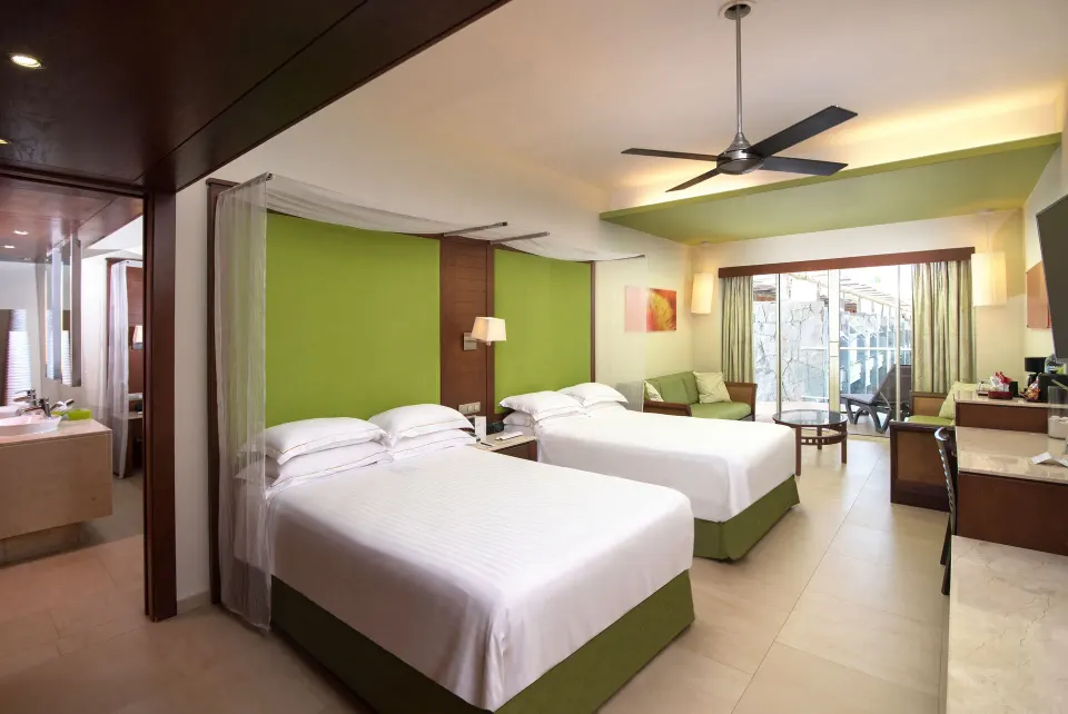 Junior Suite family Premium Level with two beds, balcony doors, and sitting area at Barceló Bávaro Palace.