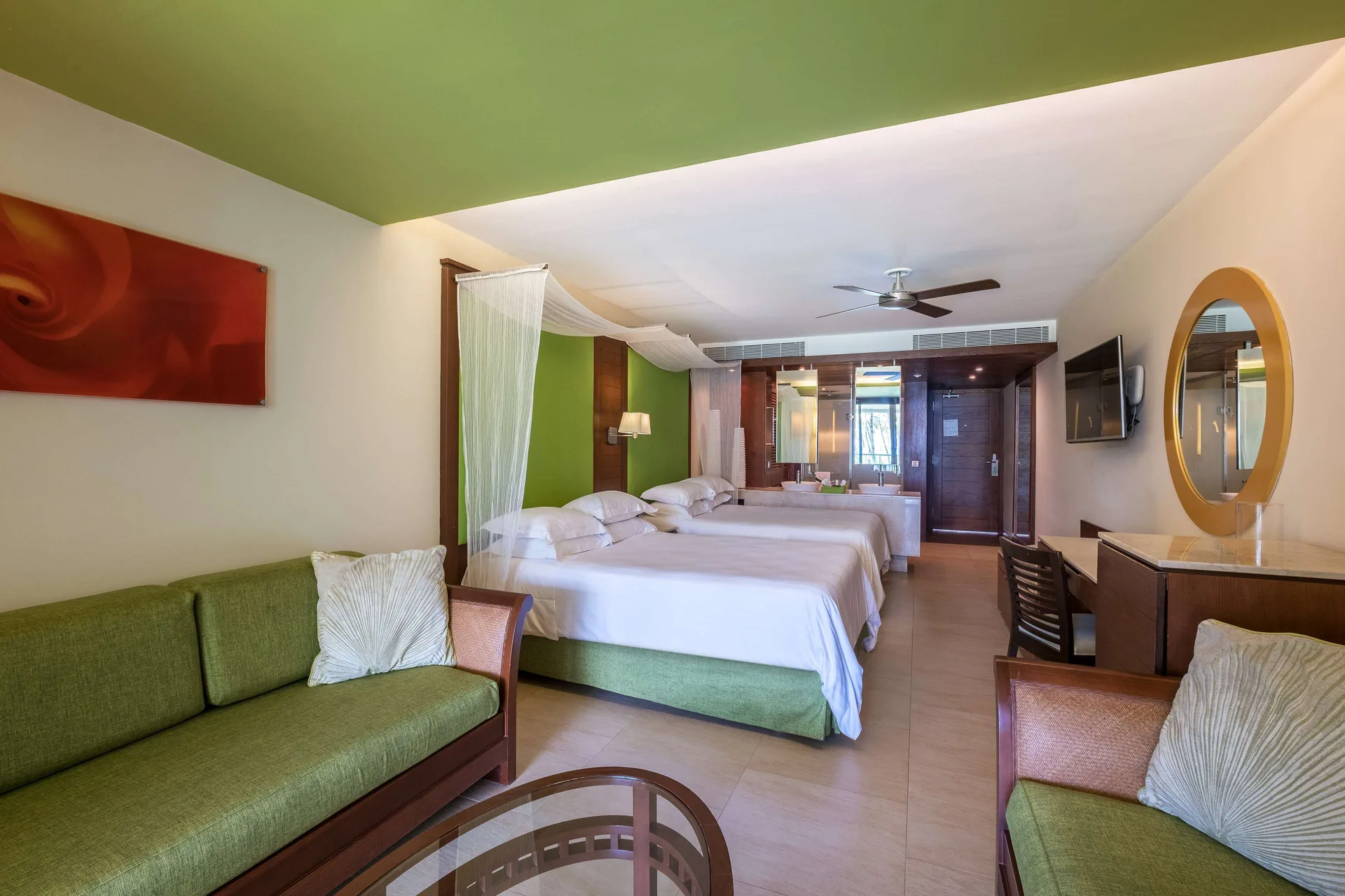 Junior Suite family Premium Level room with two beds and green sofa at Barceló Bávaro Palace.