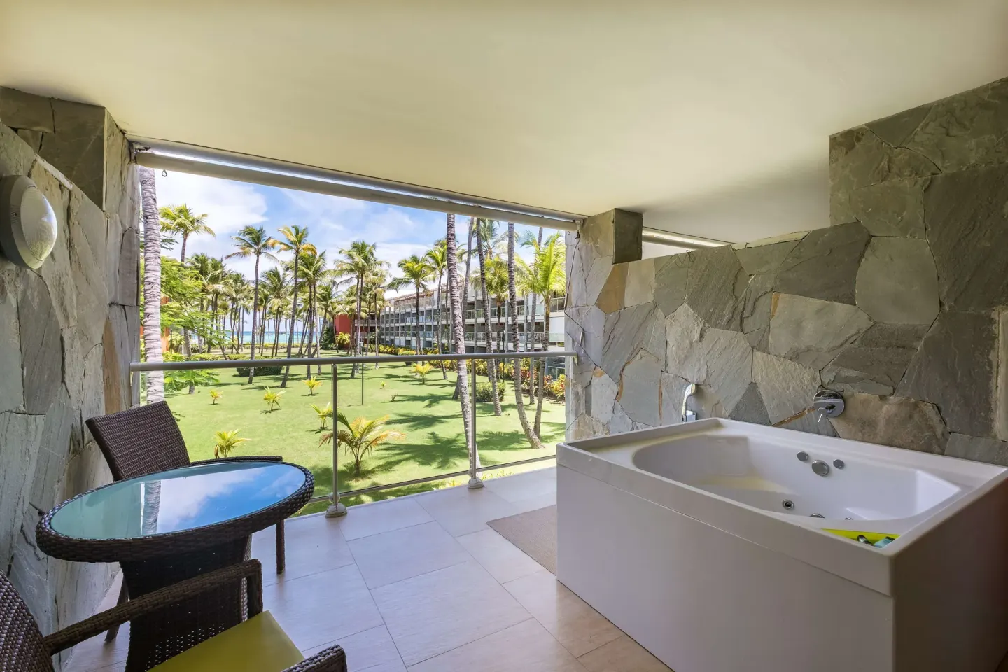 Junior Suite balcony with outdoor whirlpool tub, table, chairs, and garden view at Barceló Bávaro Palace.